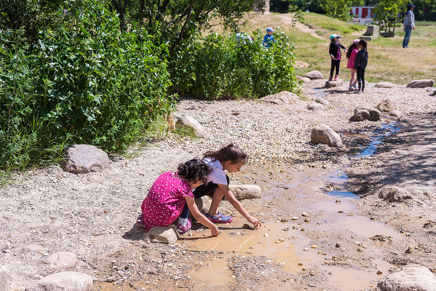 Kinder spielen am Wasserlauf des neuen Naturerfahrungsraum Tempelschlucht auf dem Tempelhofer Feld